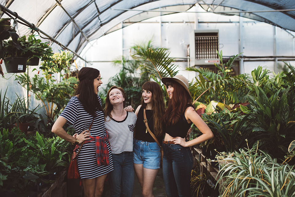 Four young women looking and smiling inside greenhouse