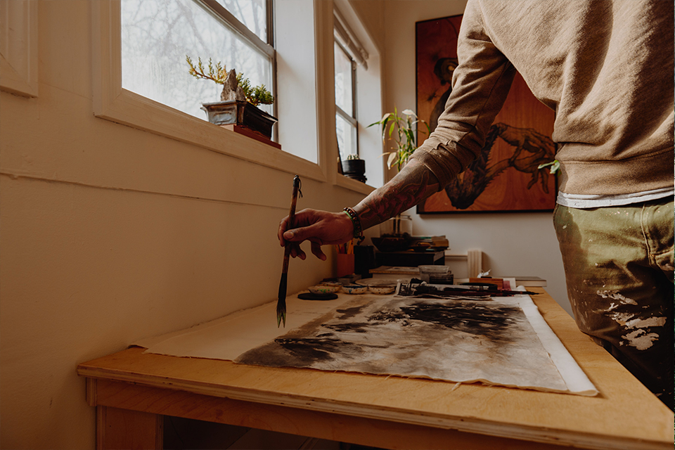 man painting japanese art callygraphy on paper