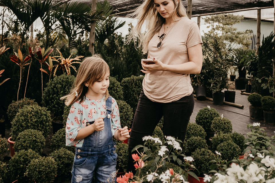 Mother and child working on plants inside small greenhouse